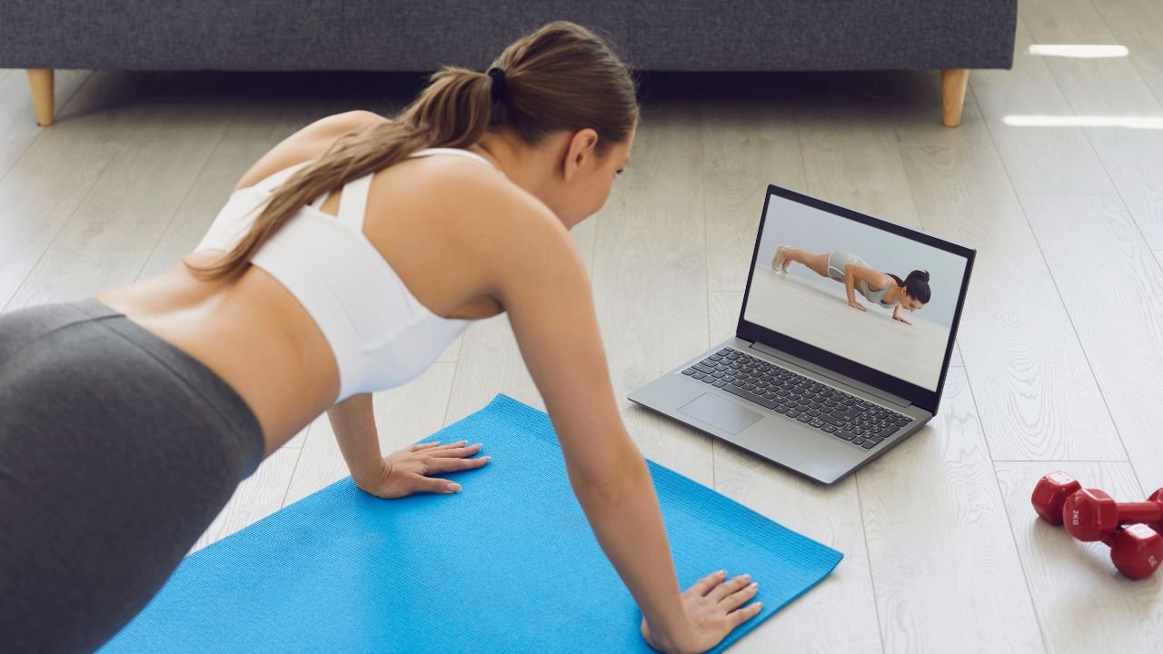 busy mom working out at home with laptop on the floor